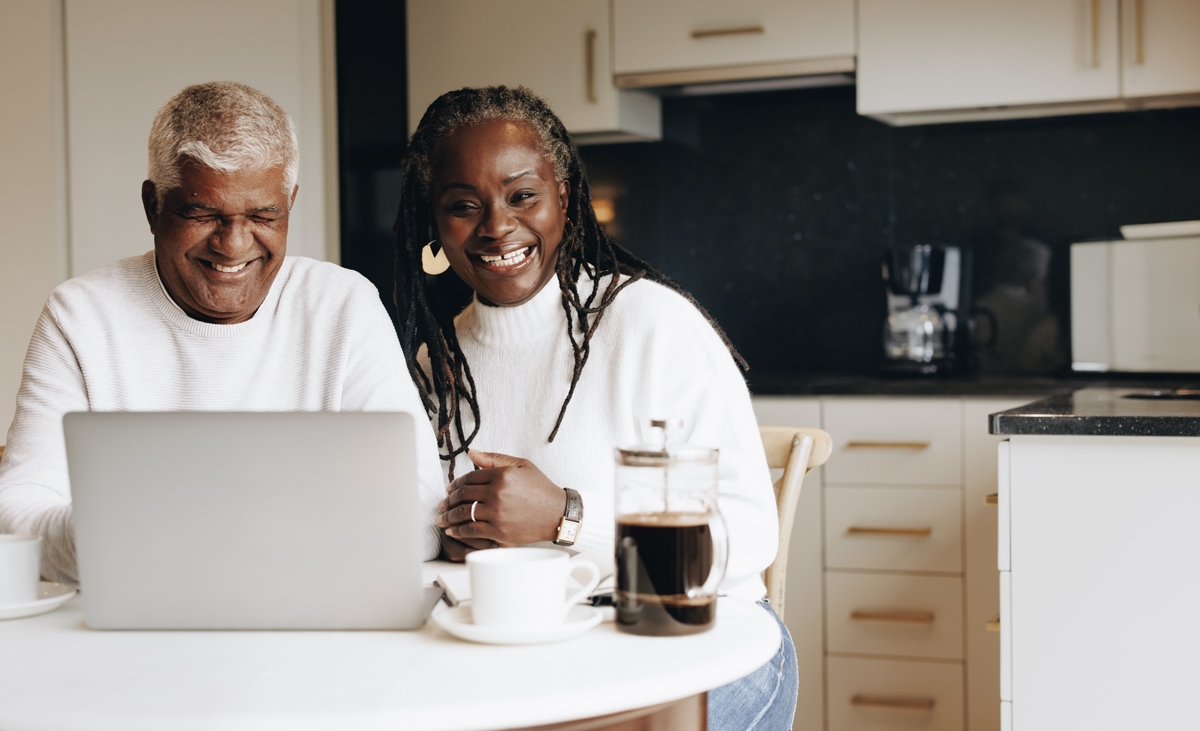 Couple sitting in the kitchen looking at their laptop