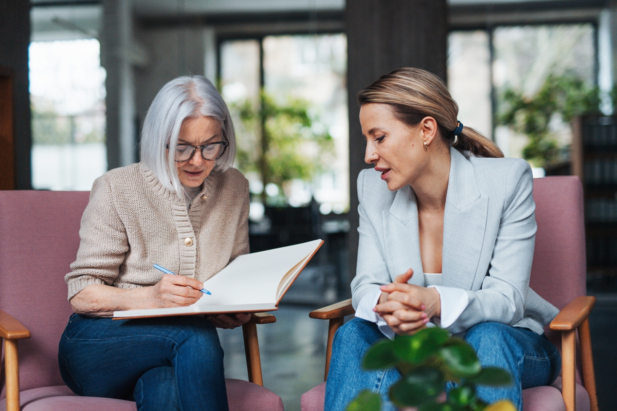 Two businesswomen sitting down looking through a book