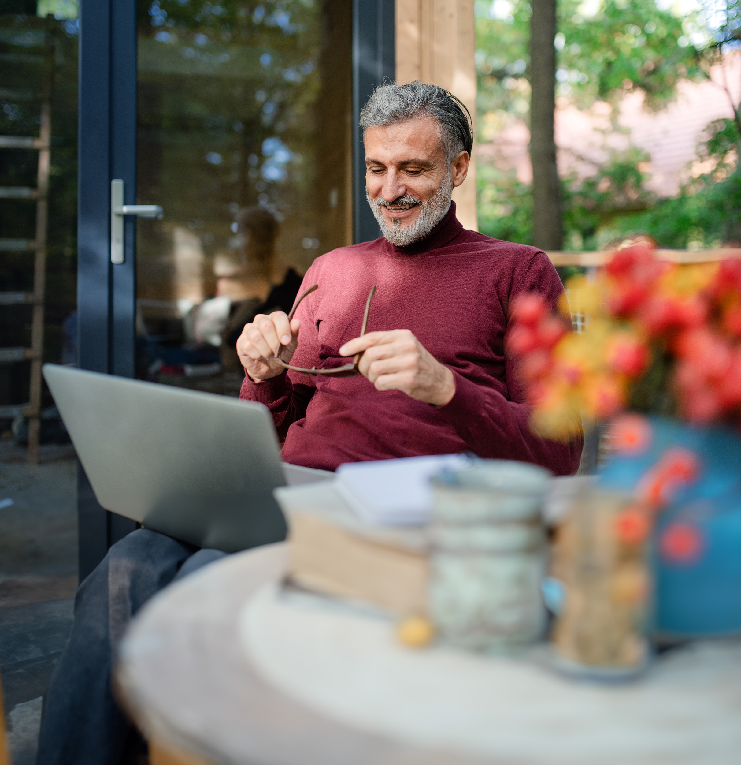 Man sitting in his garden looking at a laptop