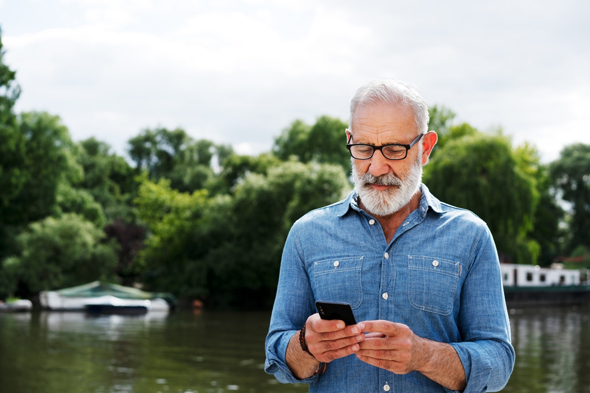 Man looking at his phone by the lake