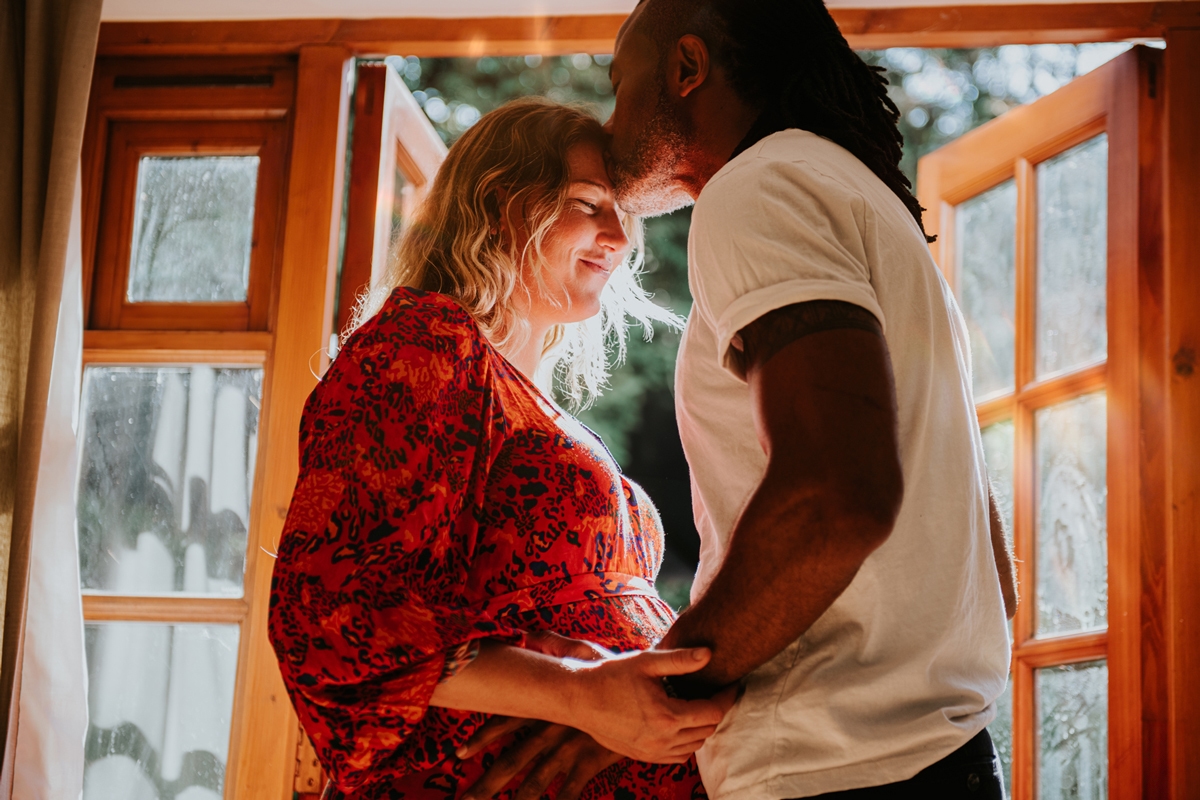 Pregnant women and man standing near an open window