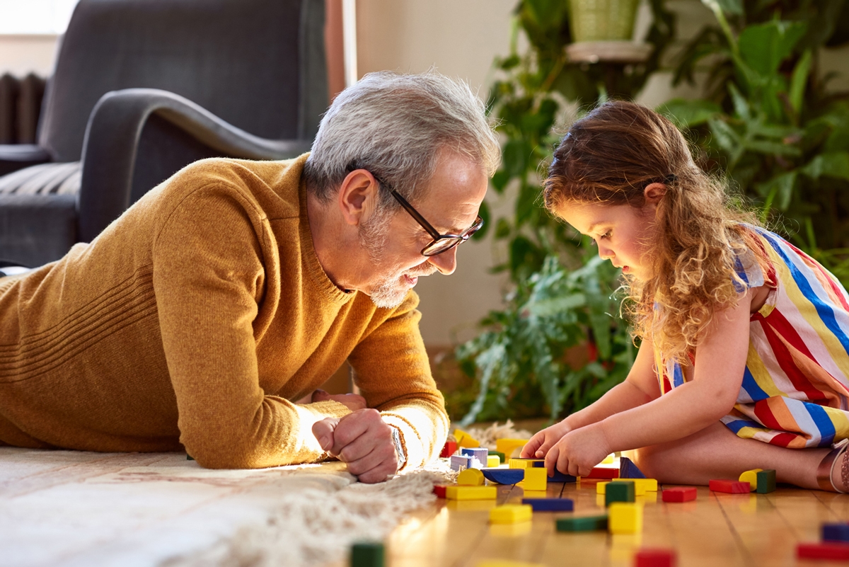 Grandfather and granddaughter playing with blocks on the floor