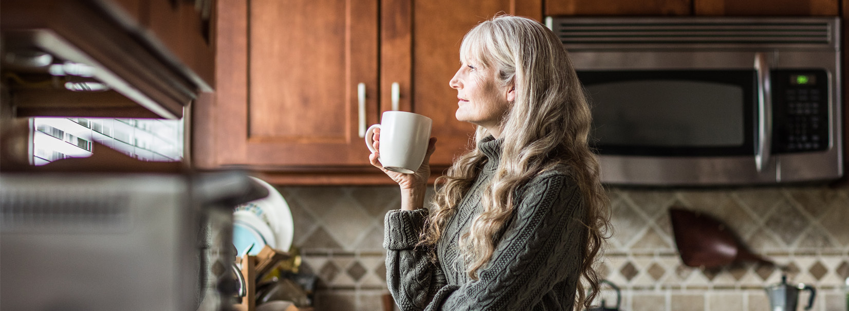 women drinking a hot drink in her kitchen