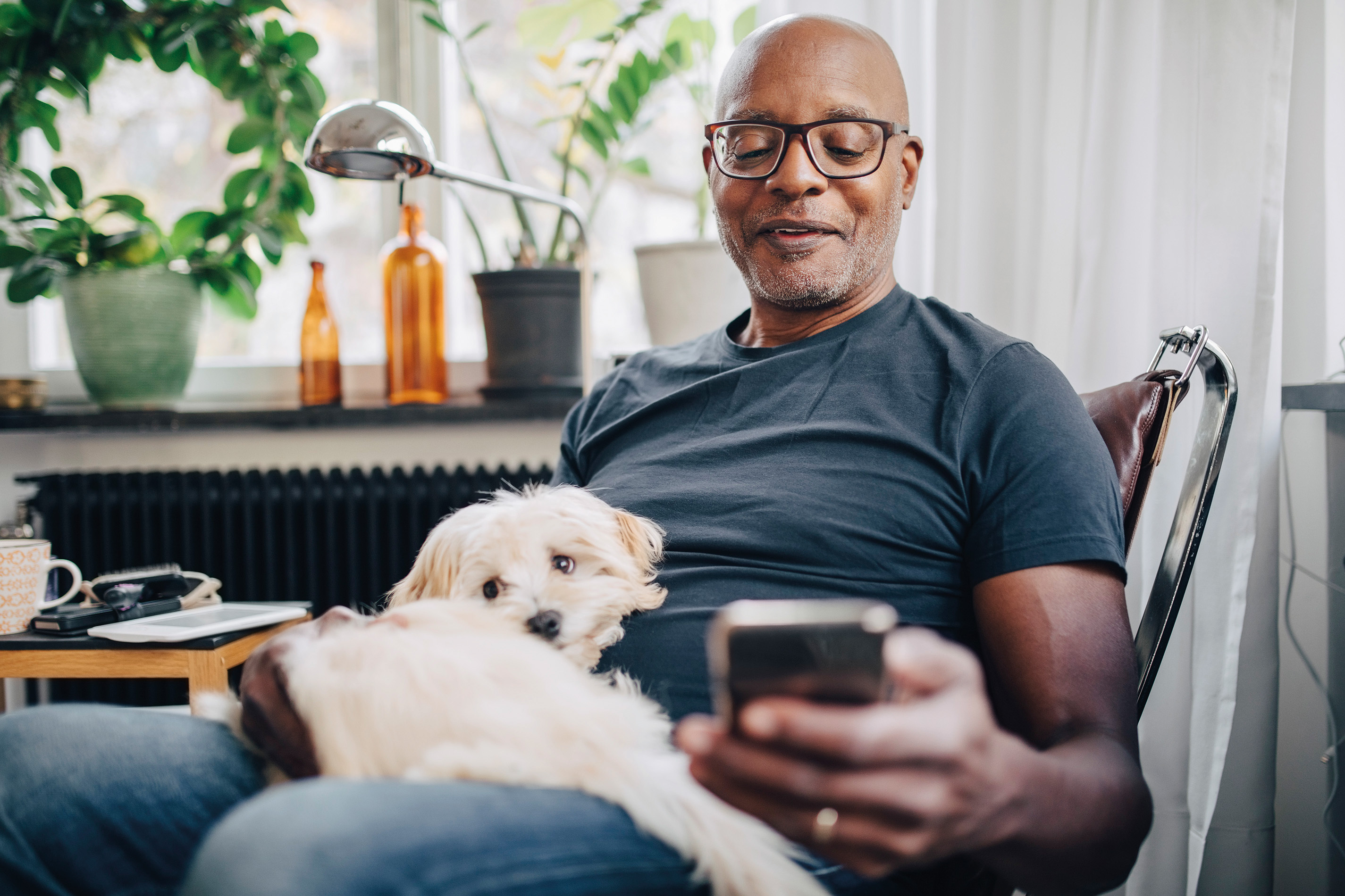 Man looking at his phone with his dog on his lap