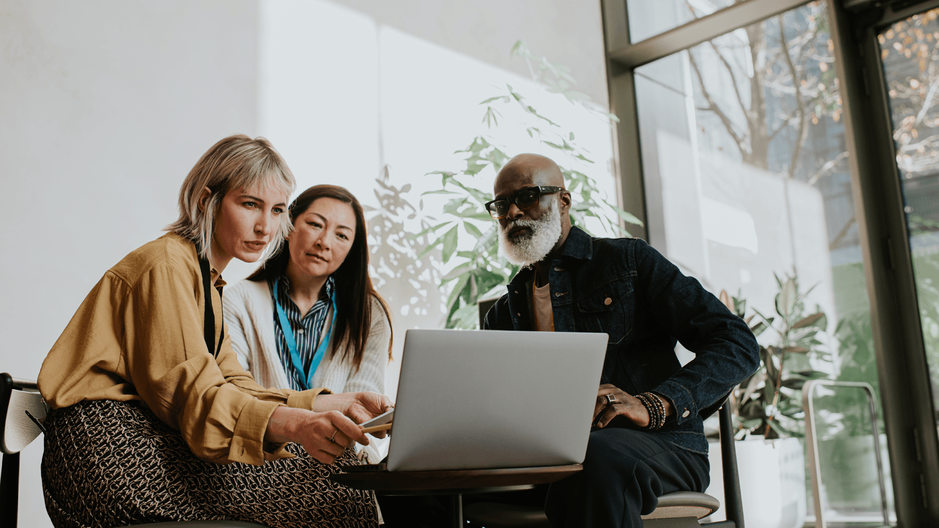 Three people sitting round looking at a laptop