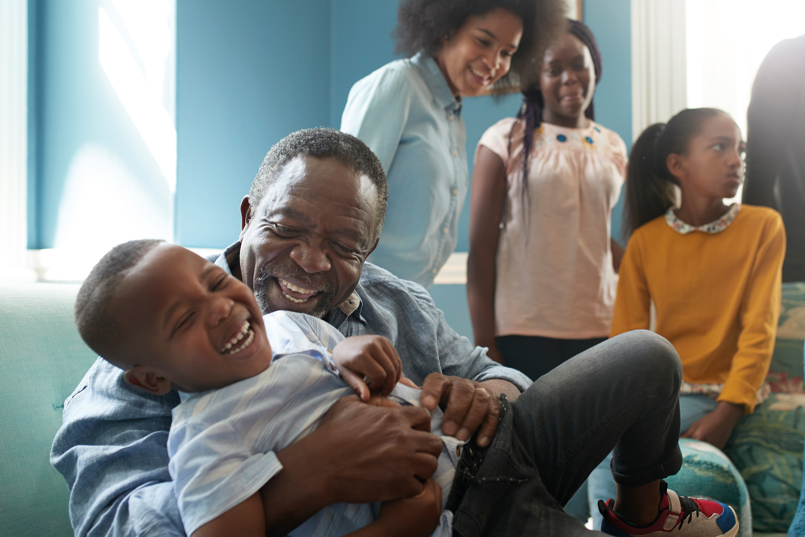 Grandfather playing with grandson with other family members in the background