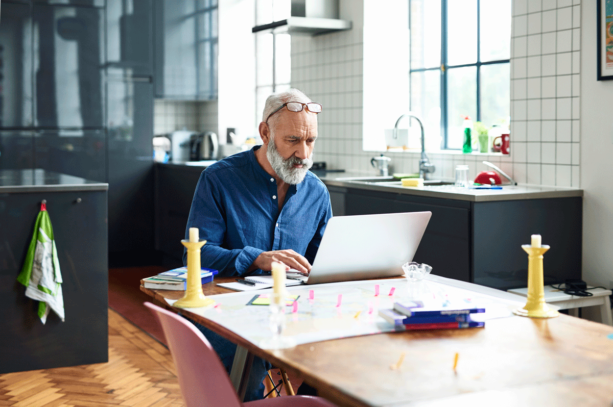 Senior man looking at his laptop in his kitchen
