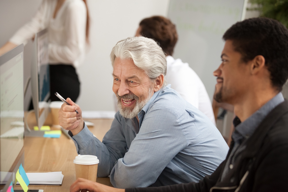 Smiling senior employee discussing email with colleague